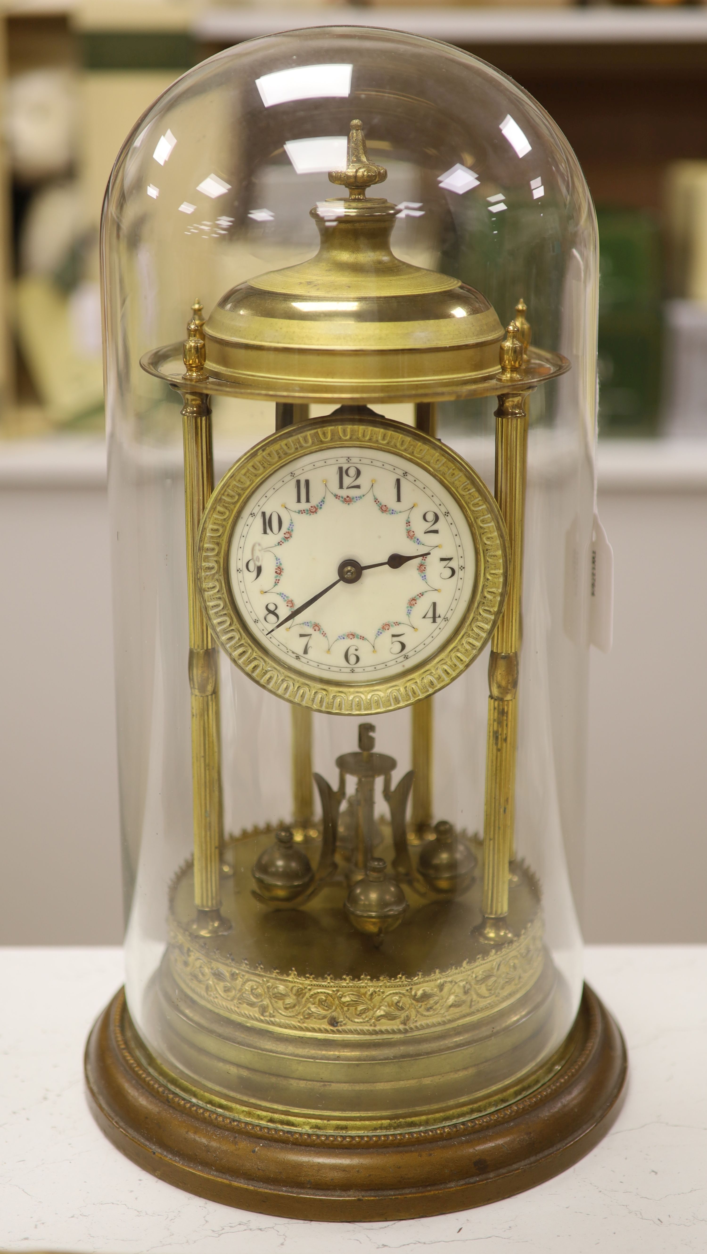 A gilt brass Anniversary clock having swag-decorated enamel Arabic dial, on circular wooden plinth under glass dome, height 42cm